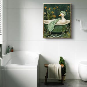 Puede incluir: Una obra de arte enmarcada representa un pato en una ba&ntilde;era verde, con un gorro verde y una toalla verde. El fondo es verde oscuro con flores amarillas y follaje. La obra de arte est&aacute; en un ba&ntilde;o con paredes de azulejos blancos.