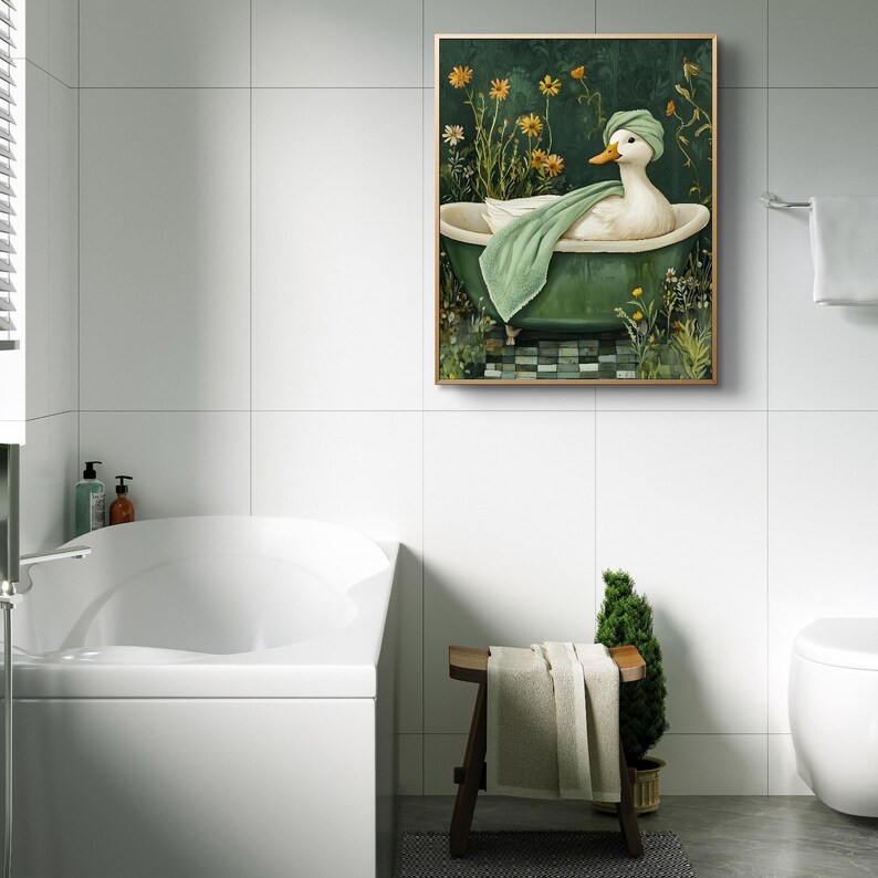 Puede incluir: Una obra de arte enmarcada representa un pato en una ba&ntilde;era verde, con un gorro verde y una toalla verde. El fondo es verde oscuro con flores amarillas y follaje. La obra de arte est&aacute; en un ba&ntilde;o con paredes de azulejos blancos.