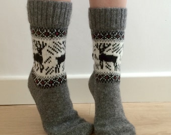 May include: Gray wool socks with a white and black reindeer pattern. The socks have a red and black trim around the top.