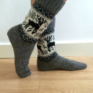 May include: Gray wool socks with a white and black reindeer pattern. The socks are folded down at the top, showing the gray wool.