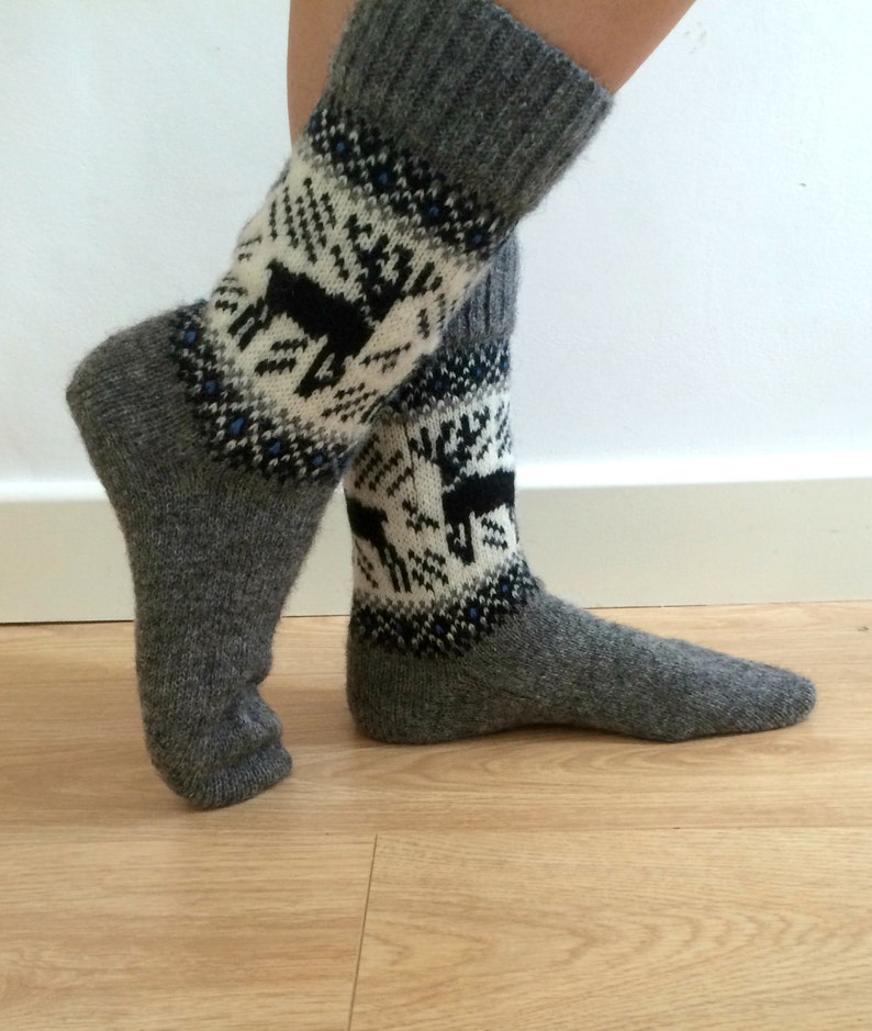 May include: Gray wool socks with a white and black reindeer pattern. The socks are folded down at the top, showing the gray wool.