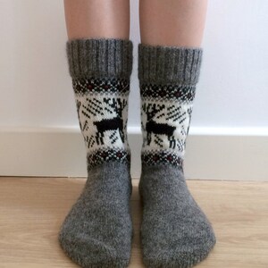 May include: Grey wool socks with a white and black reindeer pattern. The socks have a red and black trim around the top.
