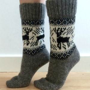 May include: A pair of gray wool socks with a white and black reindeer pattern. The socks have a blue and white geometric pattern around the top.