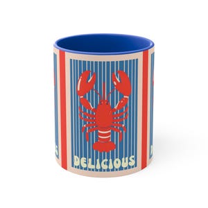 Könnte beinhalten: Keramikbecher mit blauem Innenraum und einem Design mit einem roten Hummer auf blauem und cremefarbenem Streifenhintergrund. Das Wort "DELICIOUS" ist in Creme auf dem Becher aufgedruckt.