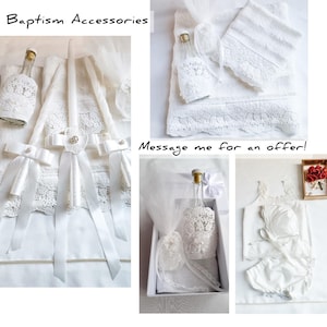 Puede incluir: Accesorios de bautizo blancos, que incluyen una vela, botellas, una toalla y un conjunto de beb&eacute;. Los art&iacute;culos est&aacute;n decorados con encaje y cintas. El texto "Baptism Accessories" es visible.
