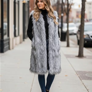 Peut inclure: Un long gilet sans manches en fausse fourrure grise et blanche à la texture hirsute. Le gilet présente une ouverture sur le devant, un ourlet droit tombant sous les hanches et des poches latérales profondes intégrées dans la fourrure longue.