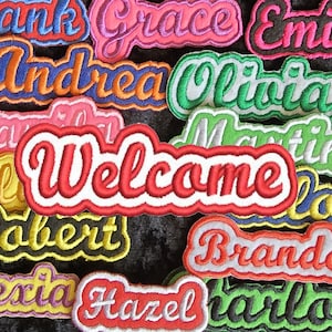 Puede incluir: Una colección de parches bordados coloridos con nombres como Frank, Grace, Emily, Andrea, Olivia, Martin, Robert, Brandon y Alexia. Los parches están todos en una fuente cursiva y tienen un contorno blanco. También hay un gran parche rojo que dice "Bienvenido".