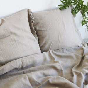 Puede incluir: Un juego de ropa de cama de lino beige con dos fundas de almohada y una funda n&oacute;rdica. La ropa de cama est&aacute; hecha de lino natural y tiene un aspecto relajado y casual.