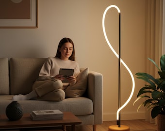 May include: A modern floor lamp with a black metal frame and a curved, illuminated white light. The lamp has a wooden base and is positioned next to a beige sofa. A person is sitting on the sofa.
