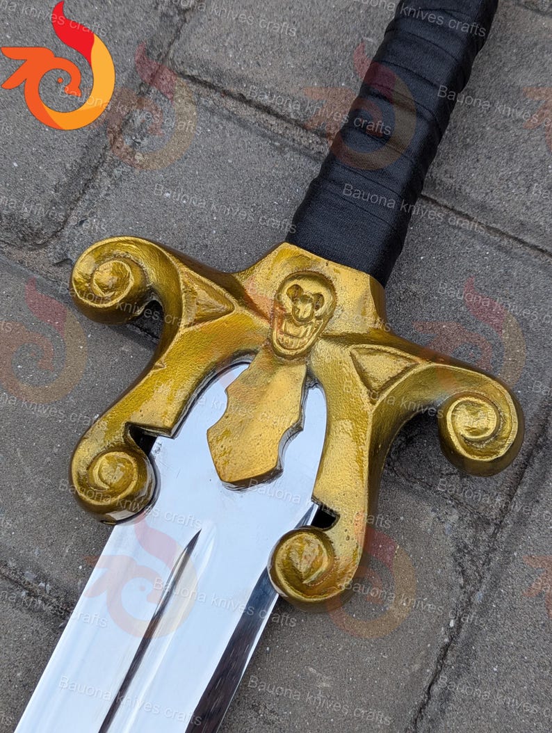May include: A detailed view of a decorative sword. The hilt is gold-coloured with a skull motif, and the blade is silver. The handle is wrapped in black. This item is likely for display or collection.