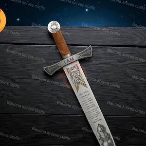 May include: A decorative sword with a wooden handle and a silver blade. The blade features etched designs and the text "I AM". The sword is displayed on a dark wooden surface.