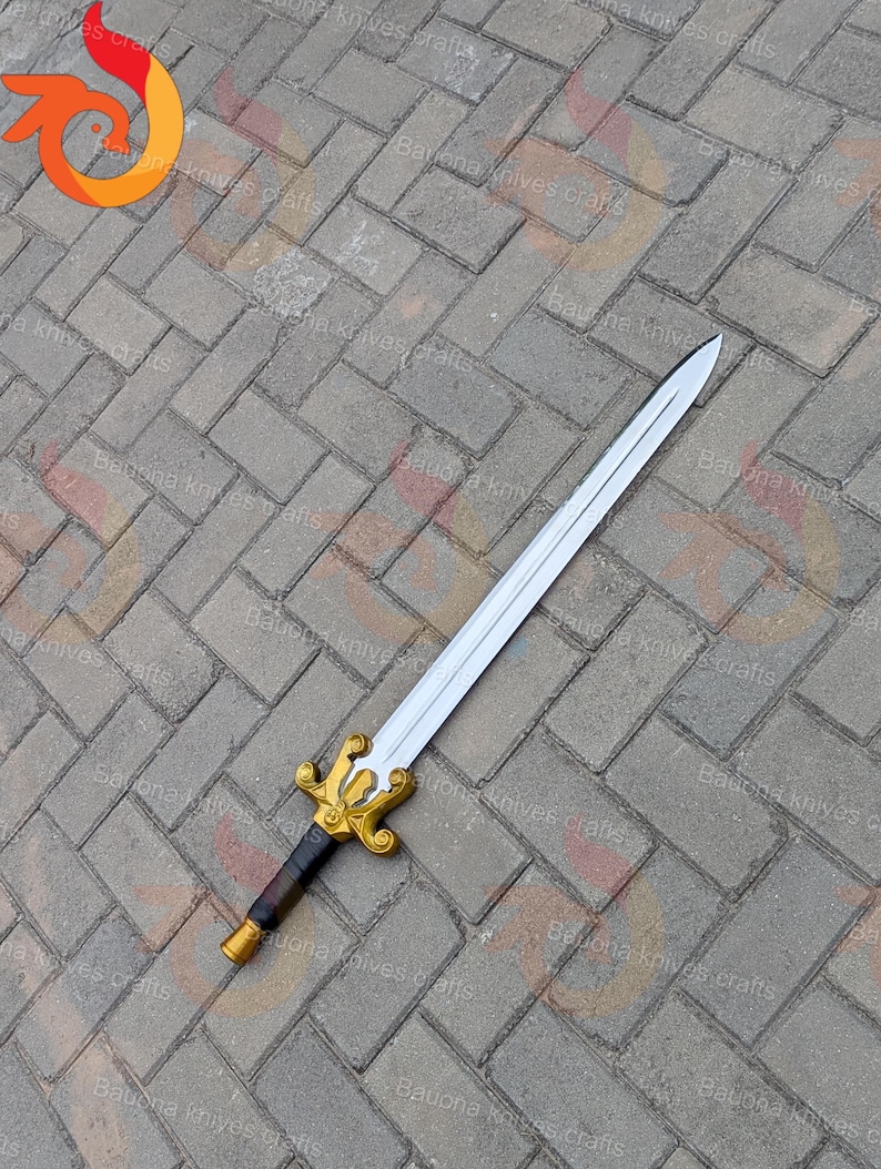 May include: A silver sword with a gold and black handle rests on a grey brick surface. The sword has a decorative gold hilt and a black grip. The blade is long and straight, with a sharp point.