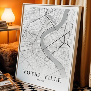 Peut inclure: Une impression encadrée d'une carte de ville, avec un plan de rues détaillé en nuances de gris et de blanc. La carte comprend une rivière et est intitulée "Votre Ville France" en texte noir. Le cadre est blanc.