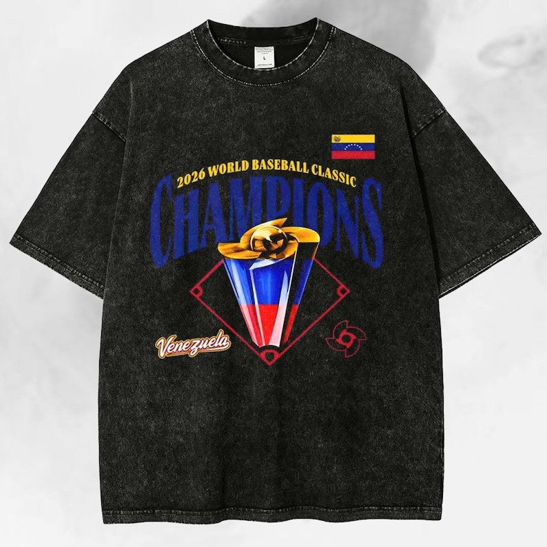 May include: Black acid wash t-shirt featuring a baseball trophy design with the text "2026 World Baseball Classic Champions" and the Venezuelan flag. The word "Venezuela" is also displayed.