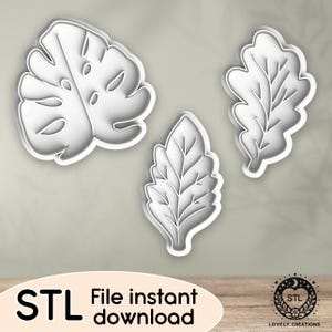 Puede incluir: Tres cortadores de galletas blancos con forma de hoja. Los cortadores incluyen una hoja de monstera, una hoja de roble y una hoja más pequeña, de forma ovalada. La imagen también incluye el texto "STL File instant download" y un logotipo.