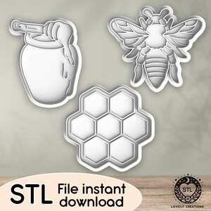 May include: Three white plastic cookie cutters: a honey pot with a dipper, a bee, and a honeycomb. The image includes the text "STL File instant download" and a logo for Lovely Creations.