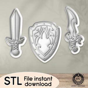 May include: Three 3D printed STL files for a sword, shield, and dagger. The shield has a decorative design with a pointed top and a rounded bottom. The swords have a simple design with a pointed tip and a handle.