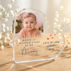 Puede incluir: Un marco de fotos acr&iacute;lico en forma de coraz&oacute;n con la foto de un beb&eacute;. El marco tiene el texto "Happy 1st Mother's Day as my Mummy" y "Lots of Love Lesley 2026" con peque&ntilde;os corazones rojos.