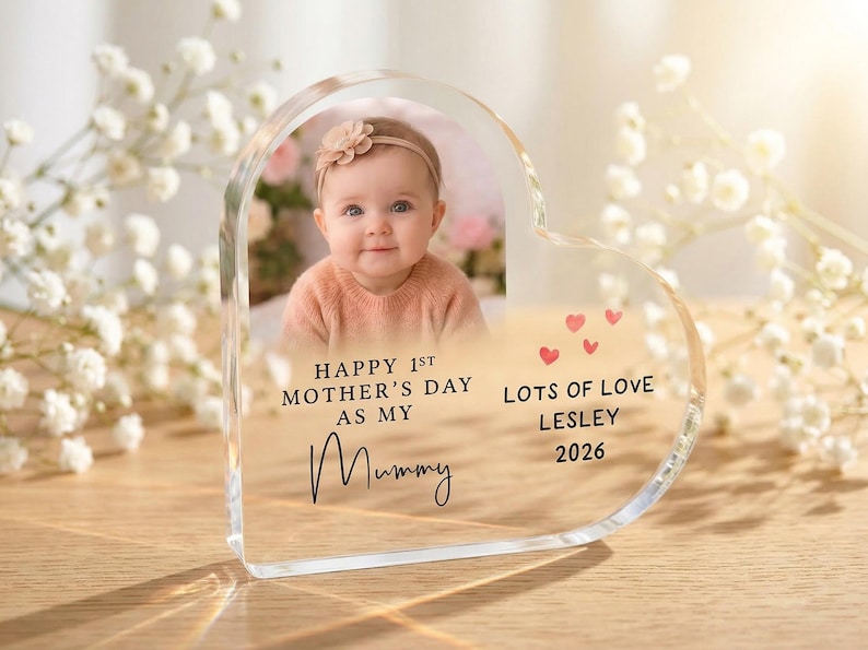 Puede incluir: Un marco de fotos acr&iacute;lico en forma de coraz&oacute;n con la foto de un beb&eacute;. El marco tiene el texto "Happy 1st Mother's Day as my Mummy" y "Lots of Love Lesley 2026" con peque&ntilde;os corazones rojos.
