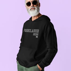 Peut inclure: Sweat à capuche noir avec l'inscription blanche "PRENZLAUER BERG BER". Le sweat-shirt a une poche avant et une capuche à cordon. La personne sur l'image porte des lunettes de soleil et un pantalon vert.