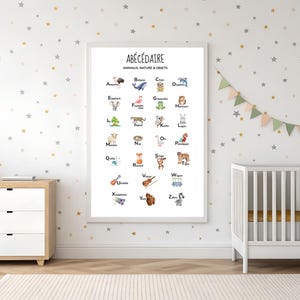 May include: A framed educational poster with the French title "ABÉCÉDAIRE" features an alphabet with animal and object illustrations. The poster is in a white frame, and the background is a star-patterned wall. A crib and dresser are also in the room.