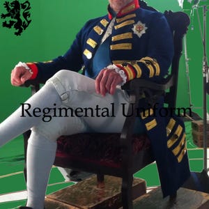 May include: A navy blue regimental uniform with gold trim, buttons, and epaulettes. The uniform features red accents on the collar and cuffs, and is worn with white breeches. The text "Regimental Uniform" is visible.