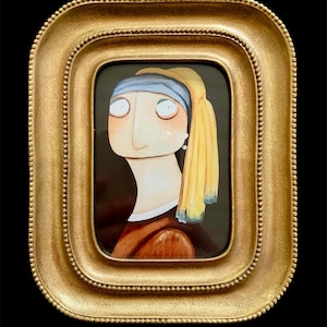 May include: A framed artwork depicting a cartoon version of the "Girl with a Pearl Earring" painting. The image is set within a gold-coloured, ornate frame. The background of the artwork is black.