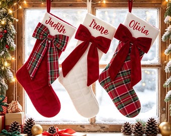Könnte beinhalten: Drei Weihnachtsstrümpfe hängen in einer Reihe. Der erste ist einfarbig rot mit einer karierten Schleife und dem Namen Judith. Der zweite ist weiß mit einer roten Samtschleife und dem Namen Irene. Der dritte ist rot-grün kariert mit einer roten Samtschleife und dem Namen Olivia.