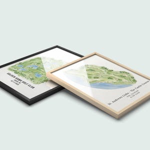 May include: Two framed watercolor prints of golf courses. One has a black frame and the text "Golden Hawk Golf Club". The other has a light wood frame and the text "St. Andrews Links - The Castle Course". The golf course illustrations are green and blue.