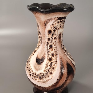 Pode incluir: Um vaso decorativo de cerâmica com uma borda ondulada. O vaso apresenta um padrão de redemoinho de marrom, creme e preto. A base é de cor marrom escuro. O vaso tem aproximadamente 20 cm de altura.