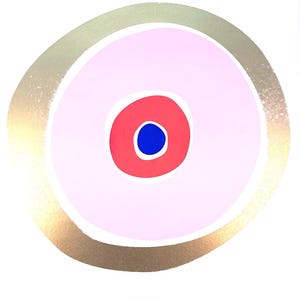 May include: Abstract art print featuring a central design of concentric circles. The artwork showcases a gold outer ring, a light pink middle circle, a red inner circle, and a small blue dot at the center, all set against a white background.