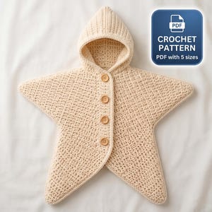 May include: A cream-colored star-shaped hooded garment made of crochet fabric with four light brown buttons down the front. A blue square icon in the corner displays the text PDF CROCHET PATTERN PDF with 5 sizes.