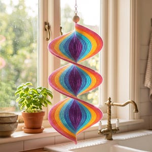 May include: A hanging spiral wind spinner featuring a vibrant rainbow gradient pattern with concentric layers of pink, orange, yellow, green, blue, and purple. The structure is composed of three connected, twisted, conical shapes suspended by a silver chain.