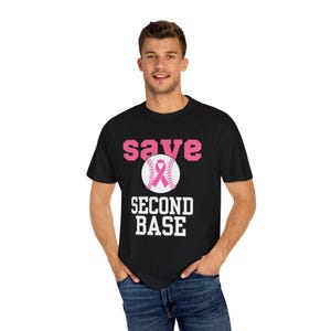 Peut inclure: T-shirt noir avec les mots "save SECOND BASE" en rose et blanc. Un ballon de baseball avec un ruban rose est au centre du motif. Le t-shirt est fait d'une matière douce et confortable.