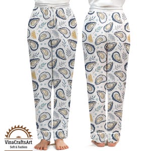 May include: White pajama pants with an all-over pattern of oysters, lemon slices, and sprigs of leaves. The pants have a drawstring waist and white trim. The VinaCraftsArt logo is visible at the bottom. Soft & Fashion.