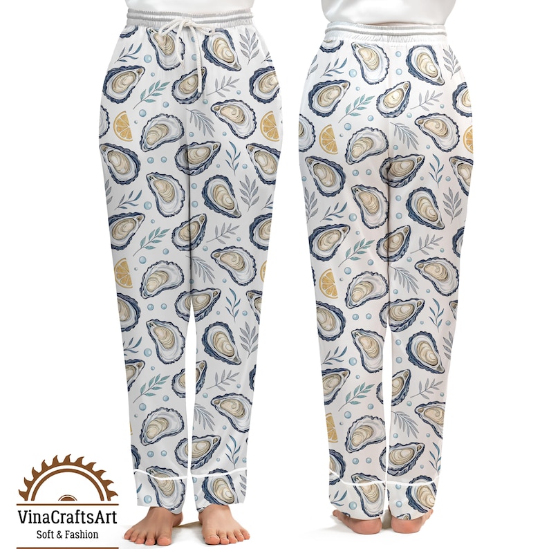 May include: White pajama pants with an all-over pattern of oysters, lemon slices, and sprigs of leaves. The pants have a drawstring waist and white trim. The VinaCraftsArt logo is visible at the bottom. Soft & Fashion.