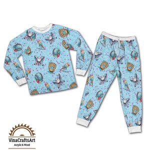 May include: A light blue pajama set with a repeating pattern of baseballs, baseball gloves, and ice cream cones. The long-sleeved top and trousers have white cuffs and a drawstring waist. The set is decorated with pink and purple sprinkles.