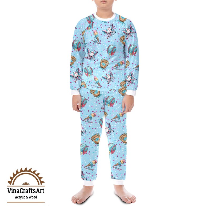May include: A light blue pajama set with a baseball theme. The long-sleeved top and trousers feature a repeating pattern of baseballs, gloves, and ice cream cones. The set has white trim and the text "VinaCraftsArt Acrylic & Wood" in the lower left corner.