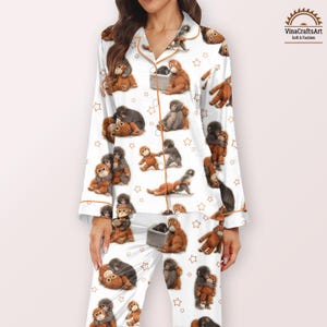 May include: White pyjama set featuring a repeating pattern of brown and grey monkeys and gold stars. The long-sleeved top and trousers have gold trim. The brand name "VinaCraftsArt" is visible in the upper right corner.
