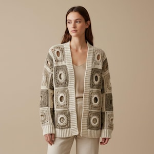 May include: A beige and brown crochet cardigan with a square pattern and open front. The long-sleeved sweater features a unique design with circular cutouts within the squares. The cardigan is made of a soft, textured yarn.