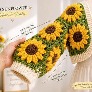 May include: A handmade crochet sleeve featuring 3D sunflower designs. The sleeve is yellow, brown, and green, with a cream-colored cuff. Sleeve width is approx. 7.5 inches (19 cm), and sleeve length is approx. 15 inches (38 cm). The text reads: 3D SUNFLOWER Size & Scale.