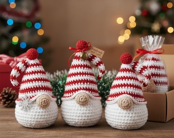 May include: Three handmade crochet gnomes with red and white striped hats and beige noses. One gnome has a snowflake attached, and another has a tag that says "Handmade with Love". A small bell is attached to the hat of the second gnome. Christmas-themed decorations.