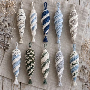 May include: A collection of ten handcrafted crochet ornaments in various shapes and colors. The ornaments feature spiral, pinecone, and leaf patterns in shades of blue, white, green, and grey, each finished with a small hanging loop and a decorative tassel.