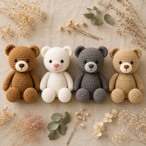 May include: Four handmade crochet teddy bears in various colors: brown, white, gray, and tan. Each bear has a round head, small ears, and a stitched nose and mouth. The bears are arranged on a neutral-colored surface with dried floral accents.