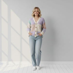 May include: A woman wearing a pastel color block cardigan with a V-neck and wooden buttons. The cardigan is paired with light wash jeans and white sneakers. The background is a plain white wall and floor.
