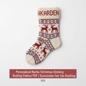 May include: A cream-colored Christmas stocking with a red and blue Nordic pattern featuring reindeer and geometric shapes. The cuff is personalized with the name "AKARDEN" in red. The text on the image reads "Personalized Nordic Christmas Stocking Knitting Pattern PDF | Scanvinalan Fair Isle Stocking NEW".