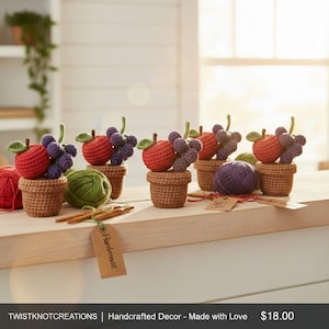 Può includere: Arrangiamenti di frutta all'uncinetto fatti a mano con mele rosse e uva viola in piccoli vasi marroni. Sono visibili anche filo verde e uncinetti, insieme a un'etichetta con la scritta "Handmade".
