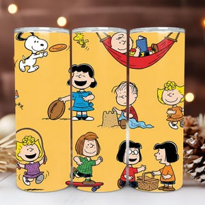 Könnte beinhalten: Gelber Becher mit Peanuts-Charakteren Snoopy, Charlie Brown, Lucy, Linus, Sally und anderen. Das Design zeigt die Charaktere beim Sport, Lesen und bei Freizeitaktivitäten. Der Becher ist ein lustiger und farbenfroher Artikel.