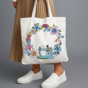 Floral sewing machine embroidery frame stitched on white tote bag, modeled with neutral outfit. Ideal for crafters, makers, and handmade business branding