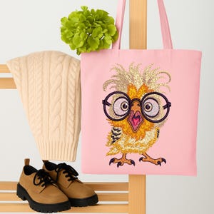 Pink tote bag featuring funny owl embroidery design with glasses, displayed with cream knit sweater, green flower, and brown shoes – great for fashion-forward embroidery lovers in the USA and Europe.